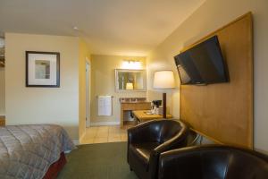 a hotel room with a bed and a chair and a television at Alpine Motor Inn in Alma