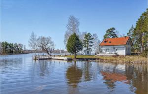 une maison assise sur le côté d'un lac avec un quai dans l'établissement Amazing Home In Hllekis With Lake View, à Lugnås