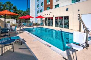 einen Pool mit Stühlen und Sonnenschirmen in einem Hotel in der Unterkunft TownePlace Suites by Marriott Auburn University Area in Auburn