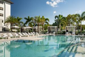 a swimming pool at a resort with chairs and palm trees at Renaissance Boca Raton Hotel in Boca Raton