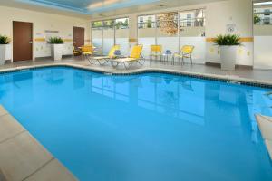 a large swimming pool in a hotel lobby with yellow chairs and tables at Fairfield by Marriott Inn & Suites Knoxville Turkey Creek in Knoxville