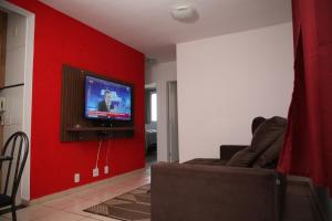 sala de estar con pared roja y TV en Apartamento Aeroporto/ Uniube, en Uberaba