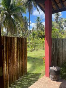 uma cerca de madeira num quintal com palmeiras em Chalés Solar do Patacho em Porto de Pedras