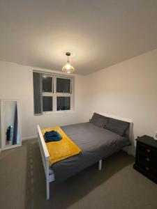 a bedroom with a bed with a yellow blanket on it at Charming Modern Apartment near London Heathrow in Feltham