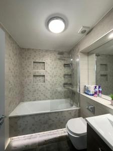a bathroom with a tub and a toilet and a sink at Charming Modern Apartment near London Heathrow in Feltham