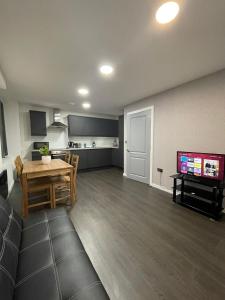 a living room with a table and a kitchen at Charming Modern Apartment near London Heathrow in Feltham