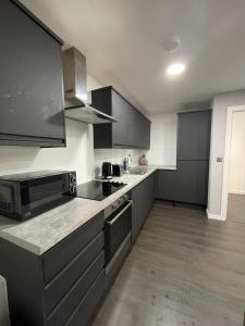 uma cozinha com armários cinzentos e uma bancada em Charming Modern Apartment near London Heathrow em Feltham
