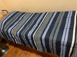 a bed with a blue and white striped sheet at Dto. CIVICO ART - PLENO CENTRO in San Juan