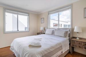a white bedroom with a large bed with two windows at Amazing Views - 3 Bed Malabar in Sydney