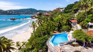 a view of a beach with a swimming pool and the ocean at Hotel Catalina Beach Resort in Zihuatanejo