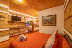 ein Schlafzimmer in einem Blockhaus mit einem Bett und einem TV in der Unterkunft Hotel Casa Elemento Villa de Leyva in Villa de Leyva