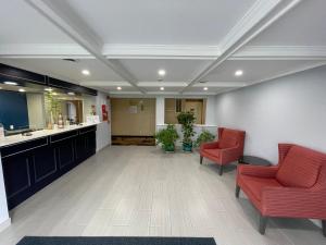un vestíbulo con 2 sillas rojas y una sala de espera en Baymont by Wyndham Branford/New Haven en Branford