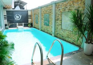 a large swimming pool with two chairs and a brick wall at Cherish Hue Hotel in Hue