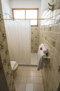 a bathroom with a toilet and a shower with towels at Hotel Catalina Beach Resort in Zihuatanejo