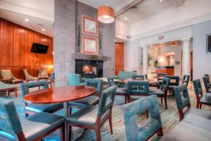 a waiting room with tables and chairs and a fireplace at Residence Inn Charlotte Uptown in Charlotte