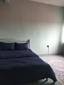 a bedroom with a bed with a blue comforter at Rumah Putih Homestay, [Mentakab near Temerloh] in Mentekab