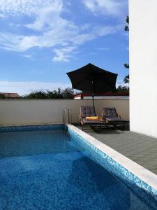 a swimming pool with an umbrella and two chairs at Apartment Iva in Šilo