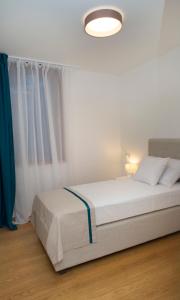 a white bedroom with a white bed and a blue curtain at Apartment Toni Delux in Split