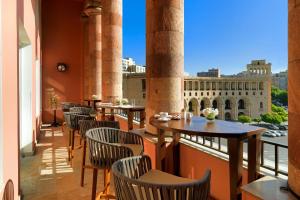a balcony with tables and chairs and a view of a building at Armenia Marriott Hotel Yerevan in Yerevan