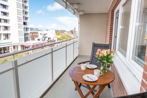 un balcón con una mesa de madera y flores. en Andreas-Dirks-Str-1-2-OG-Wohnung-207, en Westerland