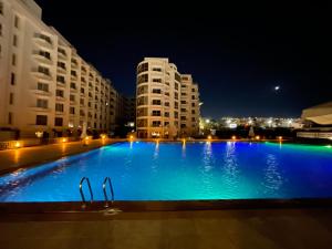 a large blue swimming pool at night with buildings at Domi Chalet in Hurghada