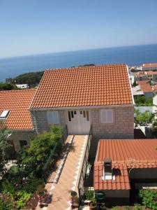 une maison avec un toit orange et l'océan en arrière-plan dans l'établissement Apartments Baltazar, à Dubrovnik