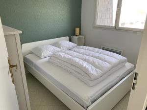 ein weißes Bett mit weißer Bettwäsche und Kissen darauf in der Unterkunft Appartement Fort-Mahon-Plage, 3 pièces, 4 personnes - FR-1-482-113 in Fort-Mahon-Plage