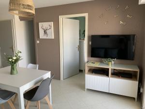a living room with a television and a table and chairs at Appartement F2 avec balcon, à 2 pas de la plage, parking privé, animaux admis - FR-1-482-113 in Fort-Mahon-Plage