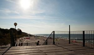 een uitzicht op het strand vanaf een houten promenade bij Wohnung mit Panoramaverglasung und Meerblick in Dziwnówek