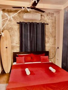 a bedroom with a red bed and a surfboard at SunshineJP Guest House and bick rentel in Weligama