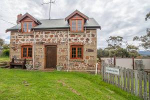 ein Steinhaus mit einem Zaun davor in der Unterkunft The Blacksmith's Cottage at Lisdillon Vineyard in Little Swanport