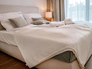 a bed with white blankets and pillows on it at Comfortable apartment overlooking the seaside beach in Niechorze in Niechorze