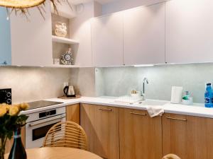 a kitchen with white cabinets and a sink and a table at Comfortable apartment overlooking the seaside beach in Niechorze in Niechorze