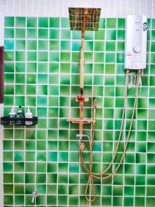 pared de azulejos verdes y baño con ducha. en Nan Bluesky Resort and Spa en Nan