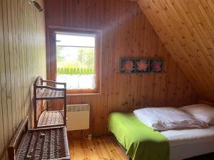 een slaapkamer met een bed in een houten hut bij DOM Z BALI Villa Bajkowy Dom in Dźwierzuty