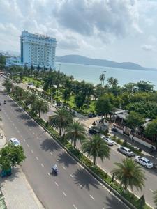 een straat met palmbomen en een groot gebouw bij Binh Minh Hotel in Quy Nhon