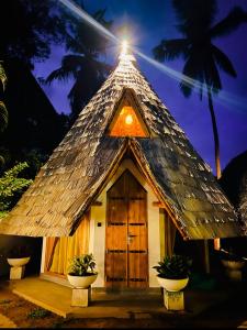 a small hut with a thatch roof with two plants at Turtle Wood Cabin in Tangalle