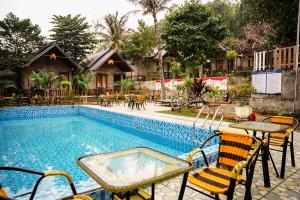 uma piscina com cadeiras e uma mesa ao lado de um edifício em Cat Ba Spring Garden Private House em Ilha de Cát Bà