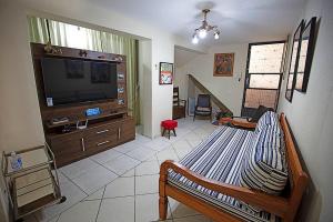 a living room with a bed and a flat screen tv at Recanto São Francisco, Casa 2 quartos 100m Igreja São Francisco Pet friend in São João del Rei