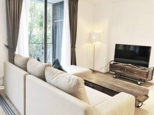 uma sala de estar com um sofá branco e uma televisão de ecrã plano em The Valley byJT em Ban Huai Sok Noi