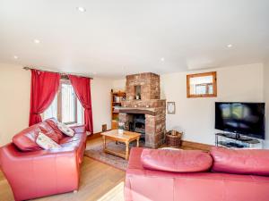 a living room with a red couch and a fireplace at Billy Croft Cottage in Knock