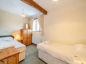 a bedroom with two beds and a desk and a window at Billy Croft Cottage in Knock