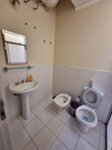 a white bathroom with a toilet and a sink at Casa en condominio a 3 minutos del Aeropuerto in Luque