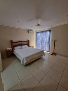 a bedroom with a large bed and a window at Casa en condominio a 3 minutos del Aeropuerto in Luque