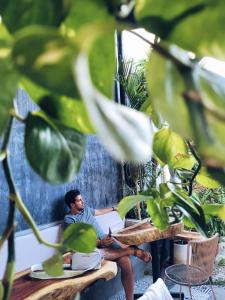 a man sitting at a table in a garden at Hoja Santa Posada in Cholula