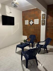 Hostal Portal del Sol في Jamundí: غرفة بثلاث كراسي وطاولة وتلفزيون