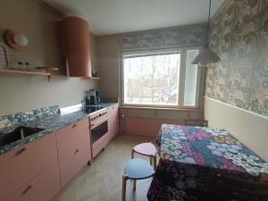 a kitchen with pink cabinets and a table and a window at Hieno kaksio keskustassa rauhallisella alueella in Lovisa