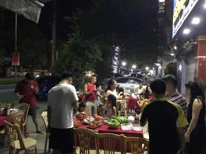 eine Gruppe von Menschen, die um einen Tisch mit Essen stehen in der Unterkunft Hai Hoa Hotel in Cửa Lô