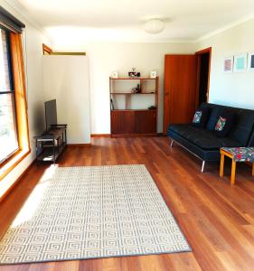 a living room with a black couch and a wooden floor at Percy's Cottage in Devonport