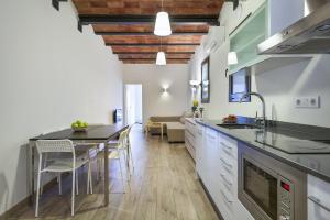 Fira Apartments by gaiarooms في برشلونة: مطبخ مع طاولة وغرفة طعام